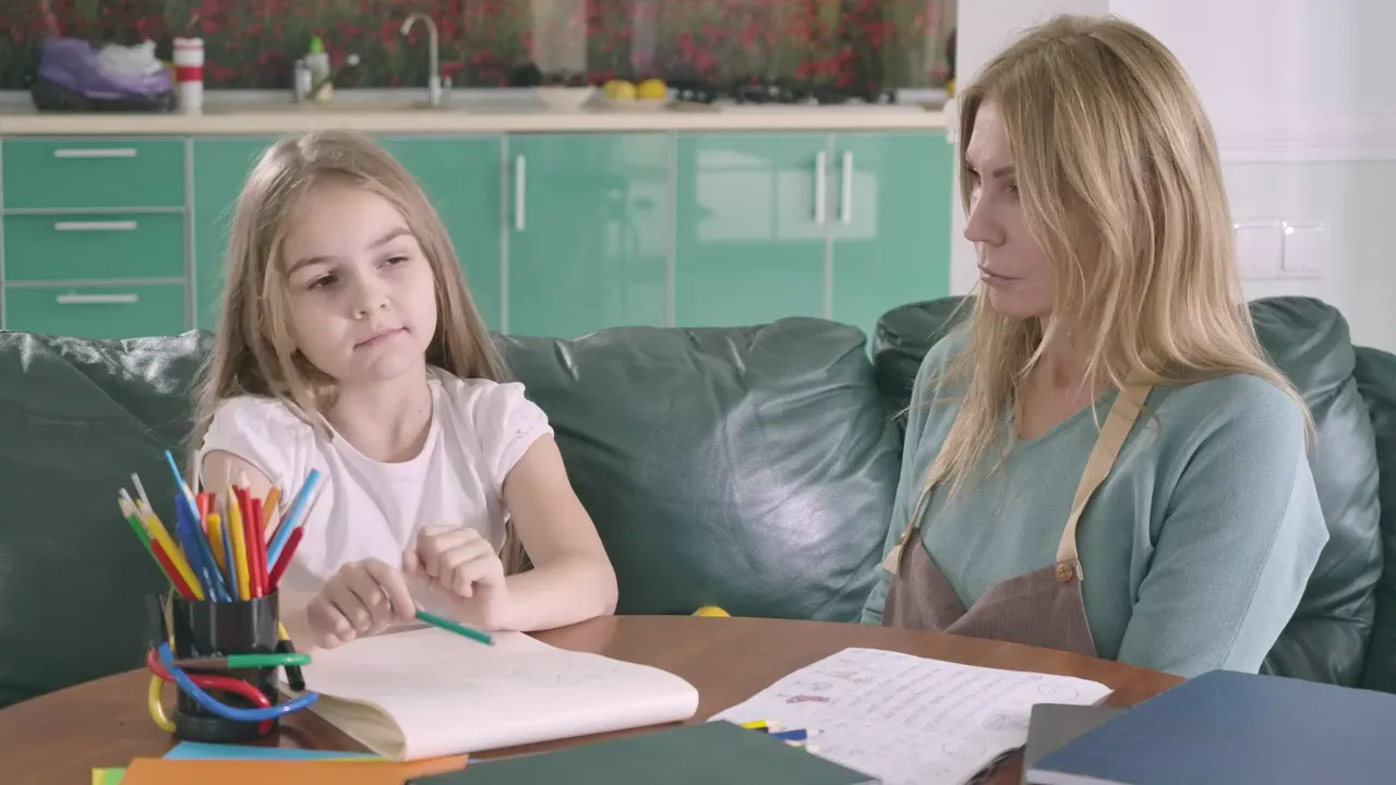 A mother helping her daughter with homework at the kitchen table